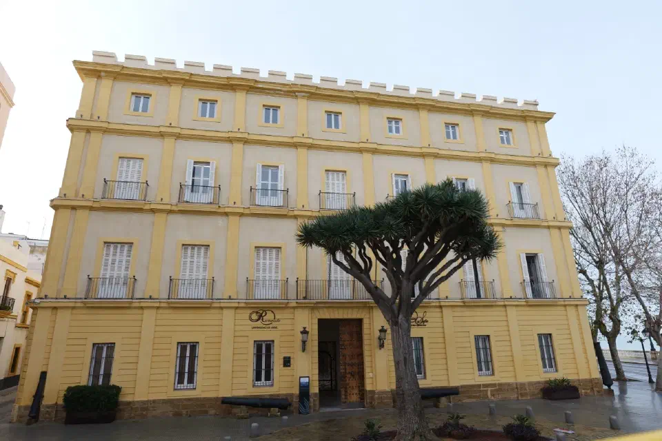 Universidad de Cádiz - ein historisches Gebäude im Herzen der Stadt, eingerahmt von alten Kanonen und einem markanten Baum.