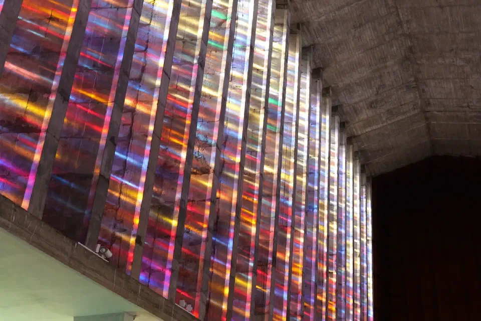 Die farbenprächtigen Glasfenster der Église Notre-Dame-de-Lourdes tauchen den modernen Kirchenraum in ein faszinierendes Spiel aus Licht und Farbe.