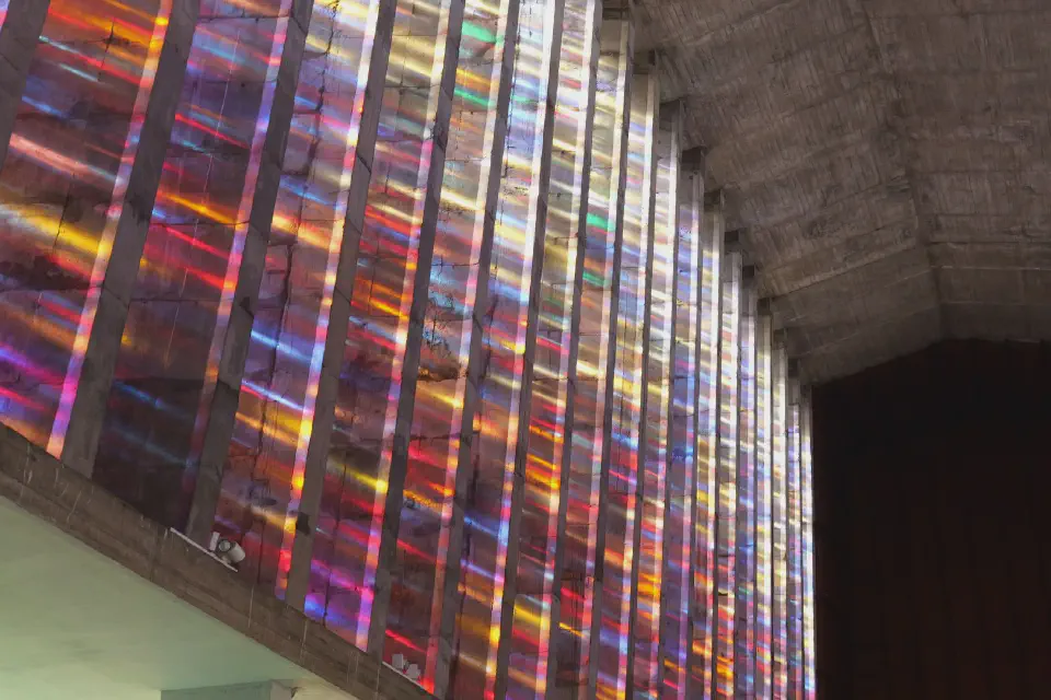 Die farbenprächtigen Glasfenster der Église Notre-Dame-de-Lourdes tauchen den modernen Kirchenraum in ein faszinierendes Spiel aus Licht und Farbe.