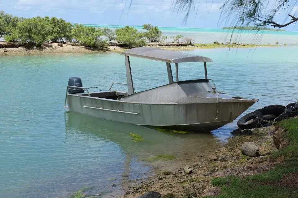 Ein einfaches Aluminiumboot am ruhigen Ufer der Lagune – ein typisches Transportmittel der Inselbewohner.