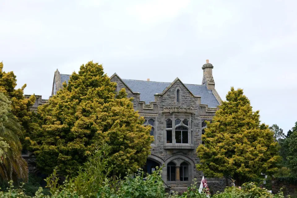 Ein historisches Gebäude in Christchurch, eingebettet in grüne Gärten und ein Beispiel für die erhaltene Architektur der Stadt.
