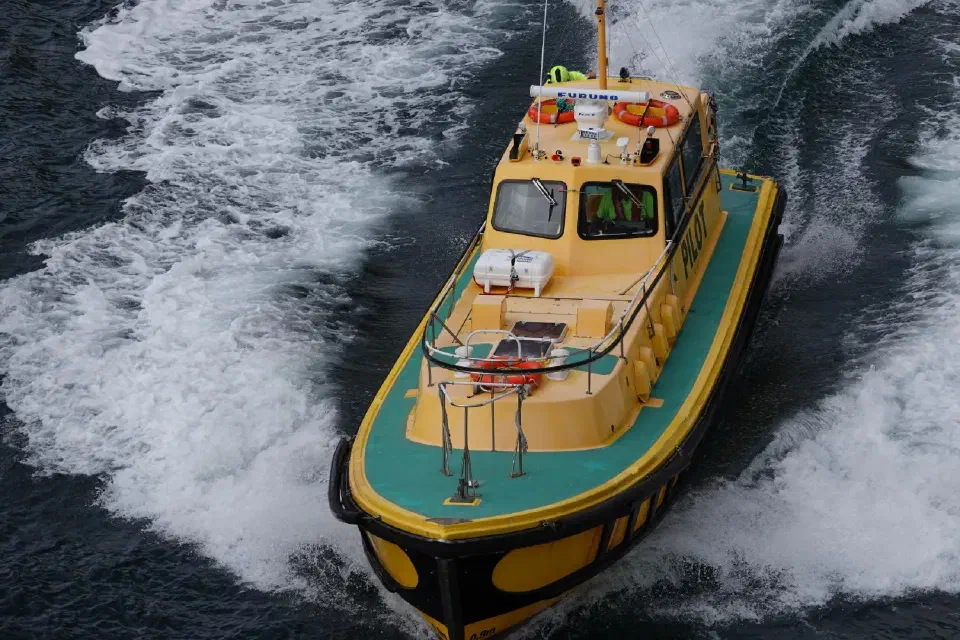 Ein wendiges Arbeits- und Begleitboot zieht seine Spur durch das dunkle Wasser des Milford Sound und unterstreicht die raue, maritime Atmosphäre des Fjords.