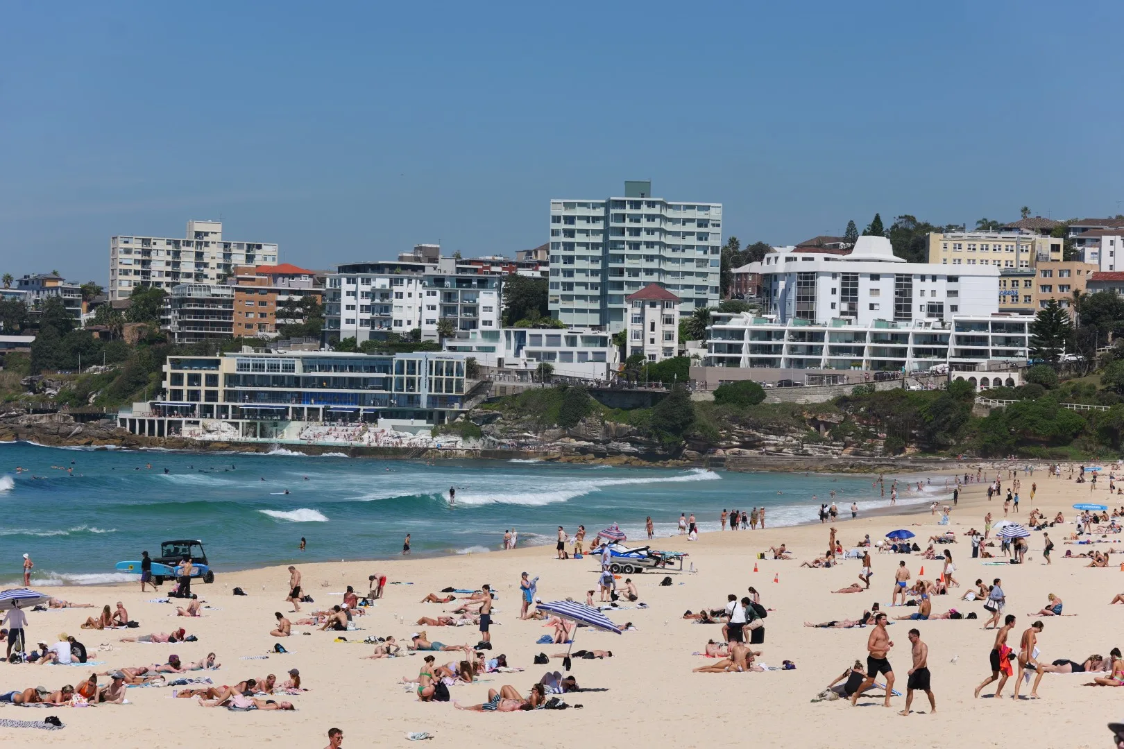 Bondi Beach zeigt sich lebendig und sonnig mit seinem breiten Sandstrand und der typischen Küstenbebauung im Hintergrund.