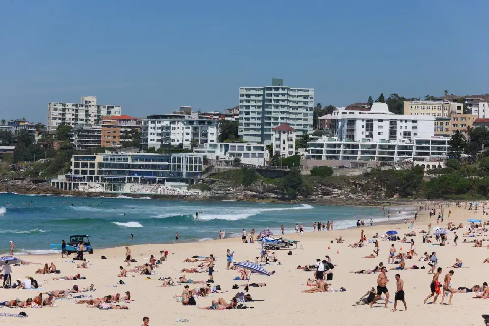 Bondi Beach zeigt sich lebendig und sonnig mit seinem breiten Sandstrand und der typischen Küstenbebauung im Hintergrund.