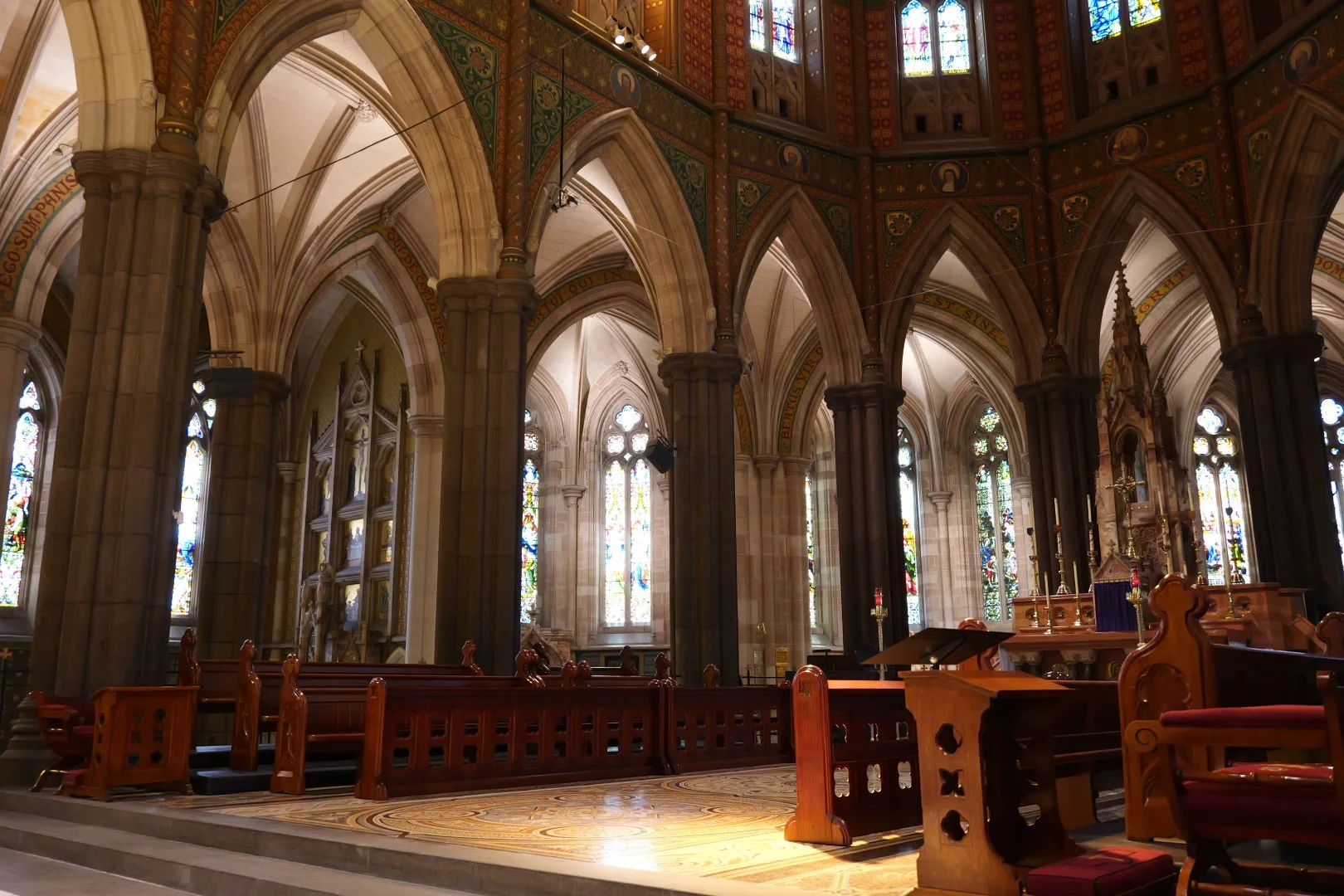 Der reich verzierte Innenraum einer Kirche beeindruckt mit hohen Bögen, bunten Glasfenstern und einer besonderen Atmosphäre der Ruhe.