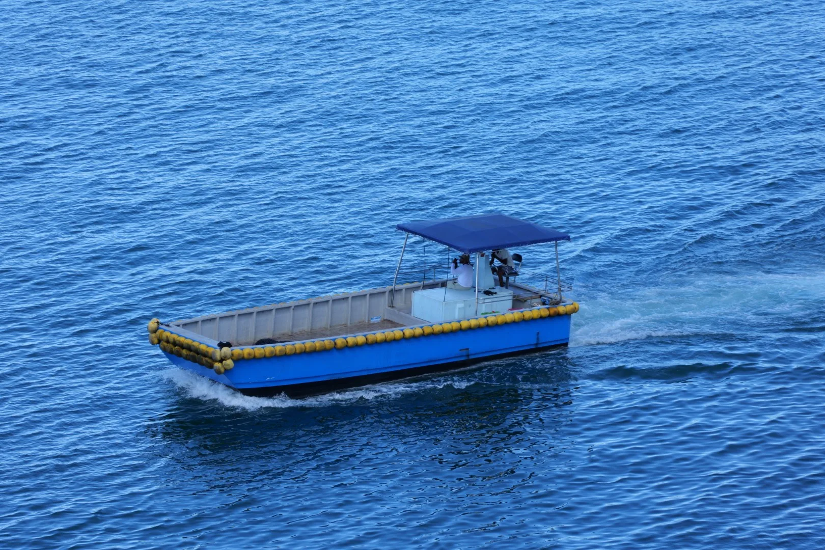 Ein kleines Arbeitsboot zieht seine Bahn über das tiefblaue Wasser vor Mahé.