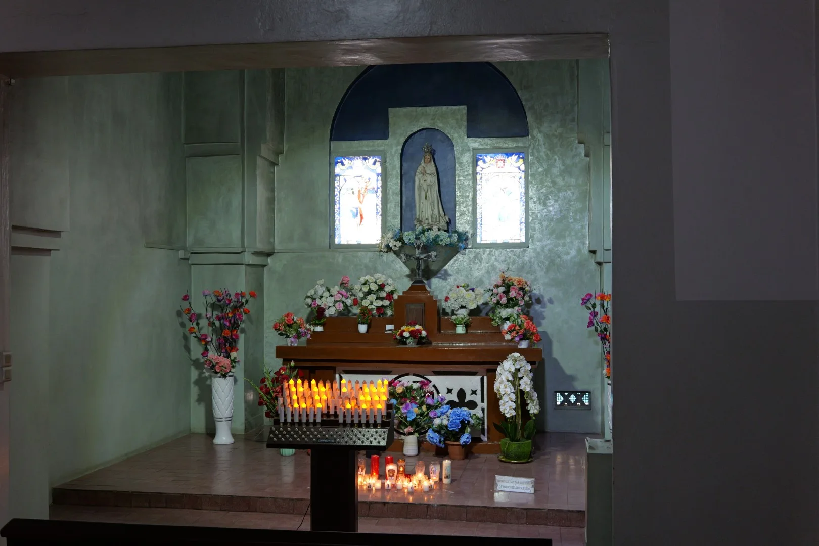 Ein stiller Ort der Andacht in Dakar – liebevoll geschmückt mit Kerzen und Blumen, der die religiöse Vielfalt und Spiritualität der Stadt widerspiegelt.